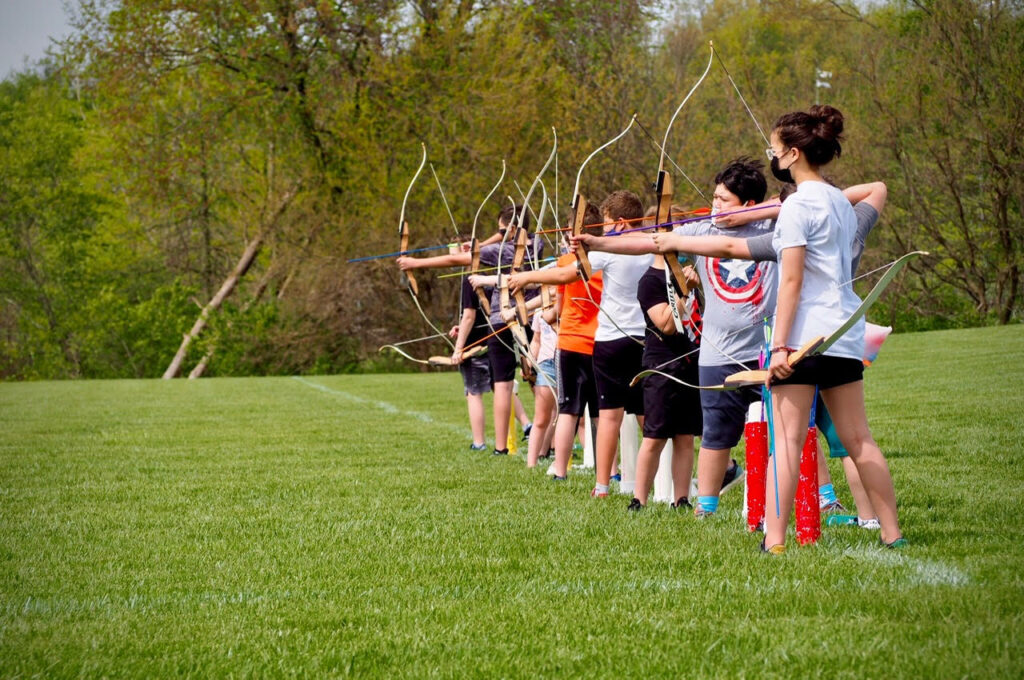 kids lined up outside practicing archery