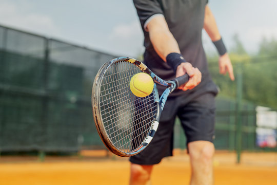 close up shot of person hitting a tennis ball with a racquet