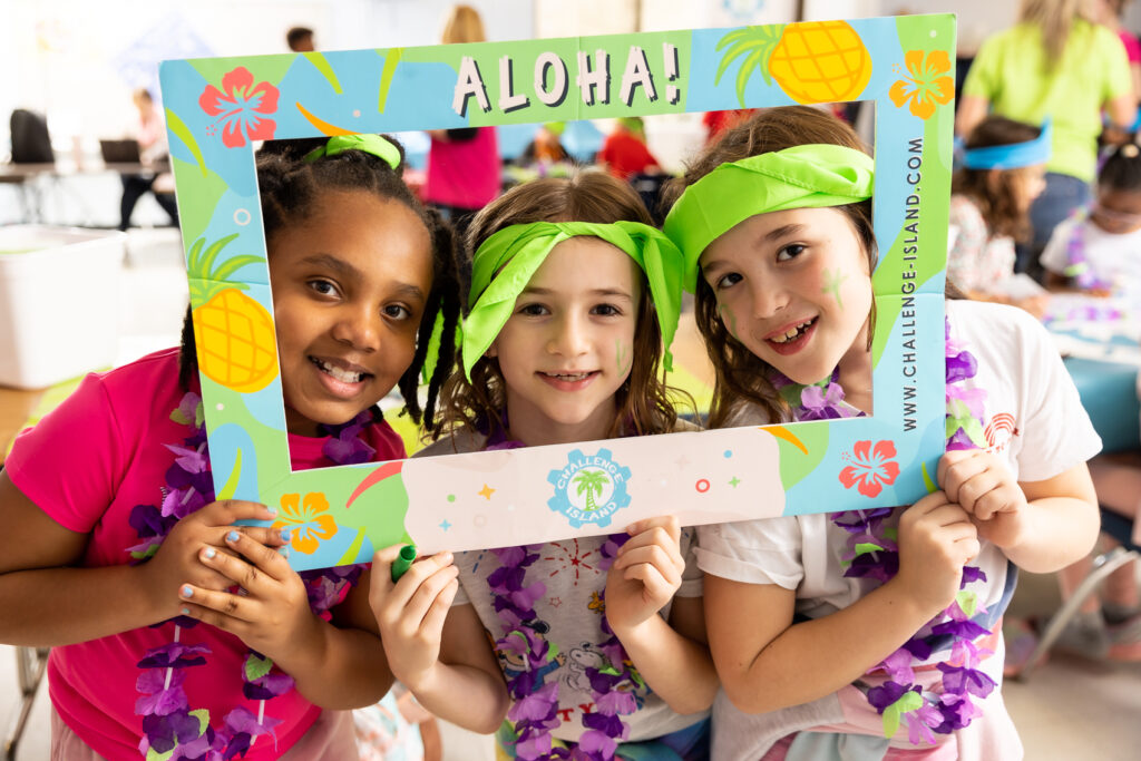 Three kids posing for the camera in a cardboard picture frame