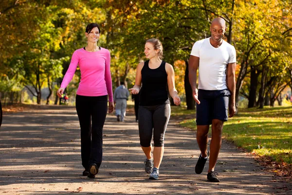 Three people walking on an outdoor path in athletic wear