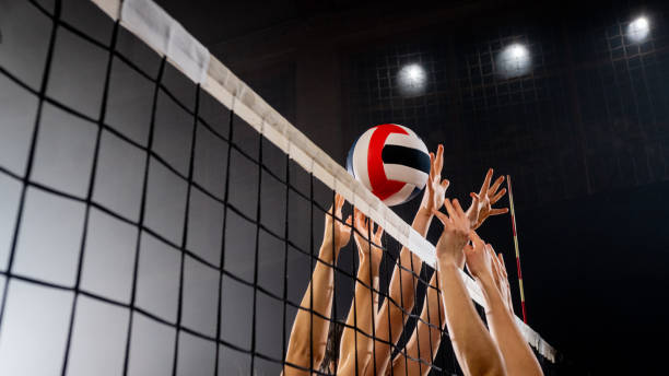 shot of hands reaching for a volleyball as it goes over the net